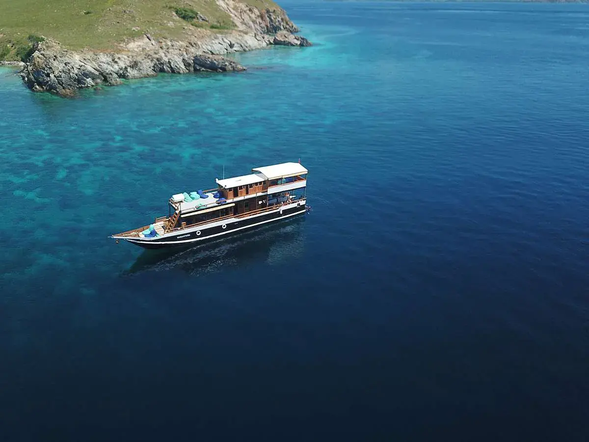 Nusantara above turquoise reefs beside a Komodo island